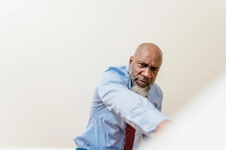 a man wearing a shirt and tie leaning against the wall