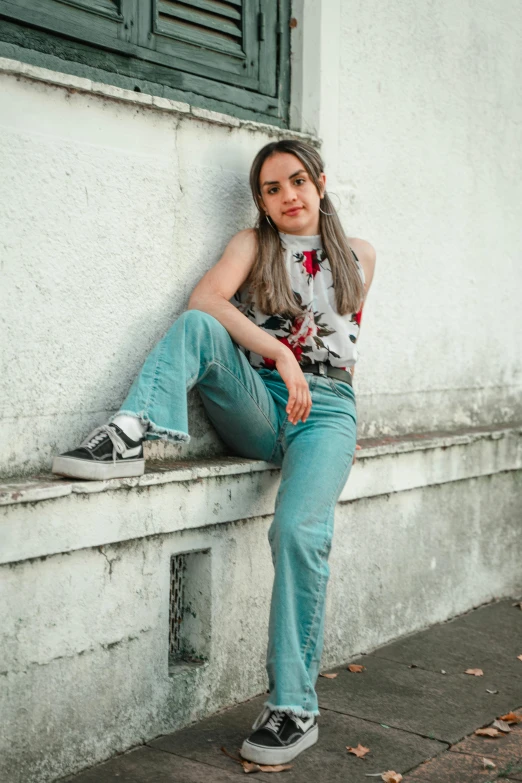 a girl sitting on a ledge with her leg up against a building