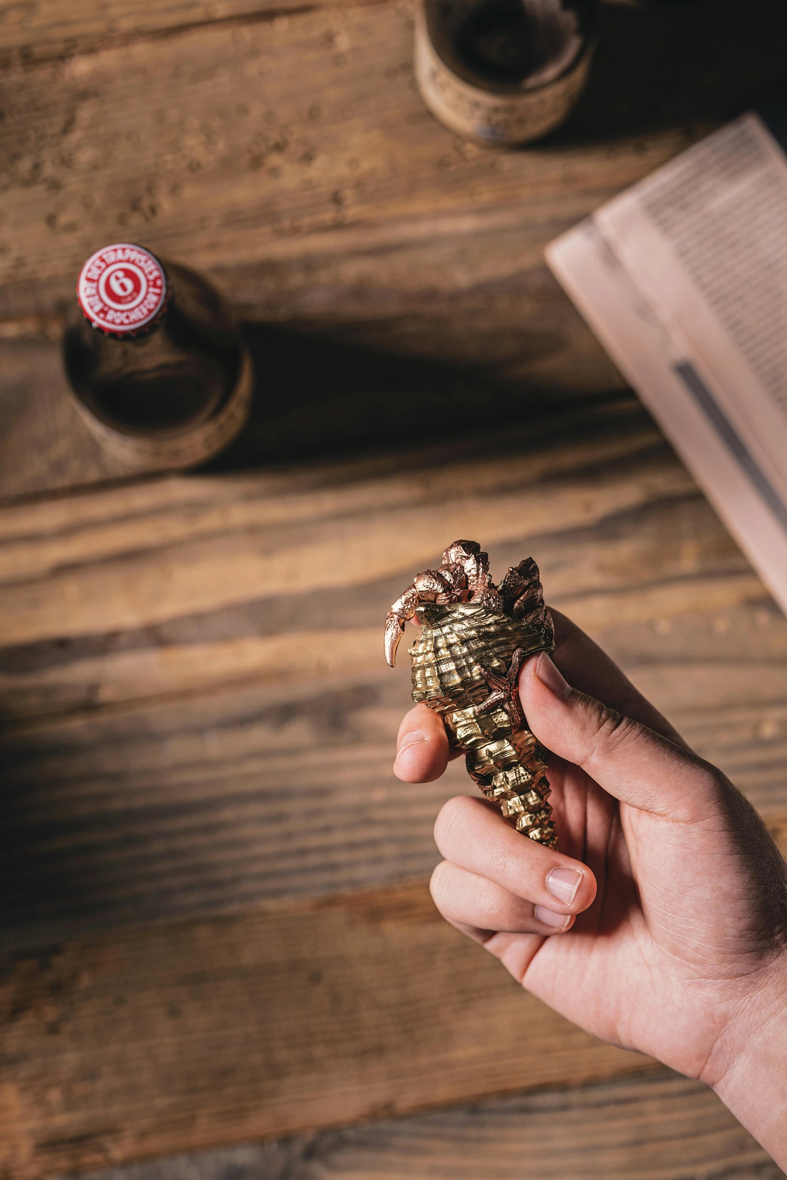 hand holding a small object near a spool of thread on a wooden table