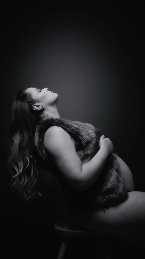 a woman sitting down on a stool in a dark room