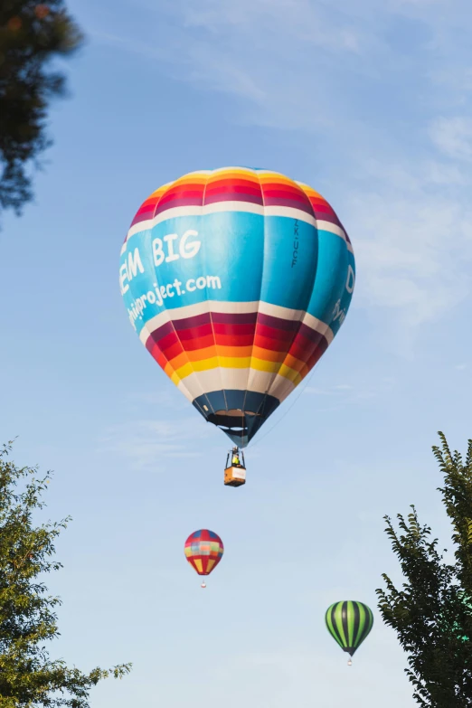  air balloons rise in the sky above trees