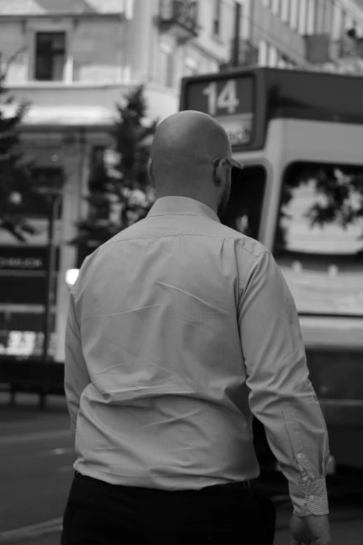 man walking down a city street past a double decker bus