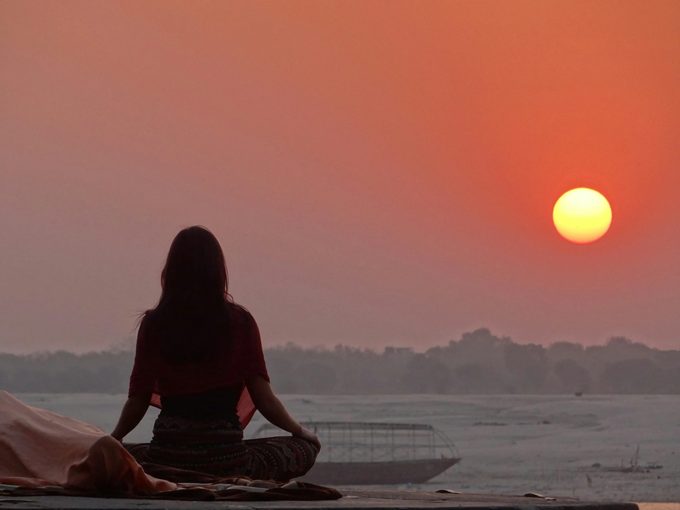 a person sitting on a beach during the sun set