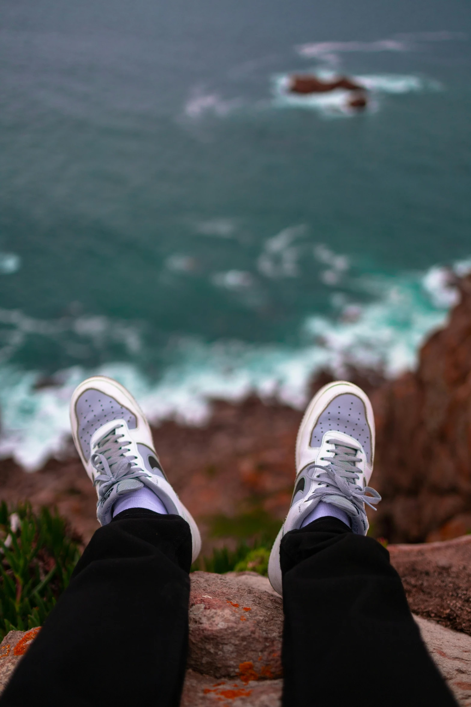 a person sits on a rock near the ocean