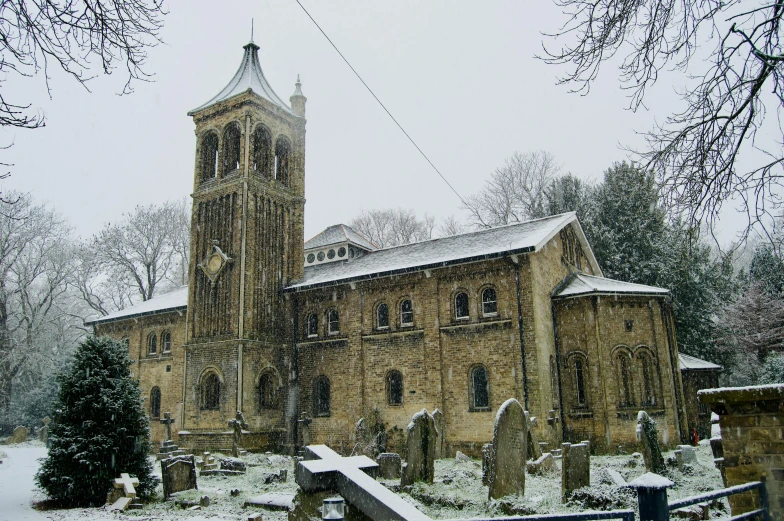 a church with a big steeple is covered in snow