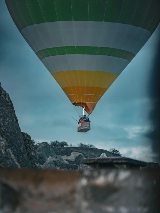 a large balloon flying over some mountains with trees in the background