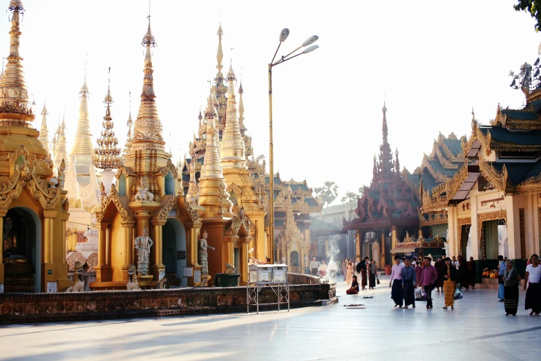 tourists walk through the street in front of some gold and ornate buildings