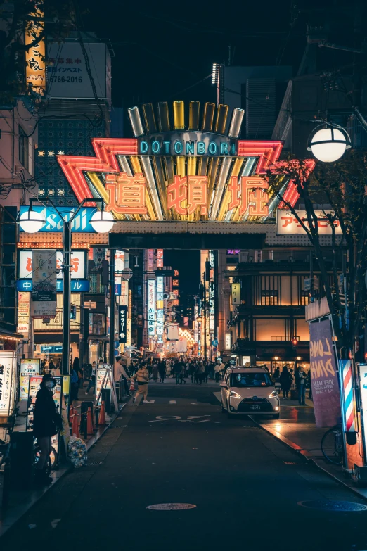 a very tall neon lit structure in the middle of a street