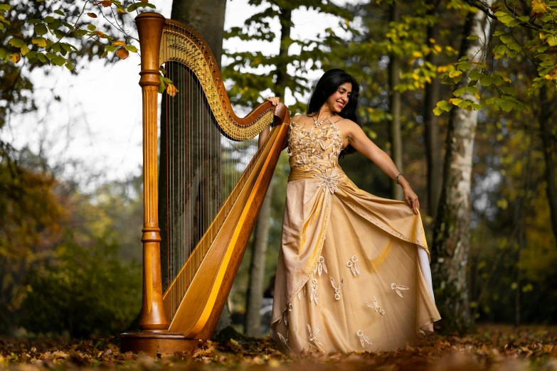 a woman in a long dress holding a large golden harp