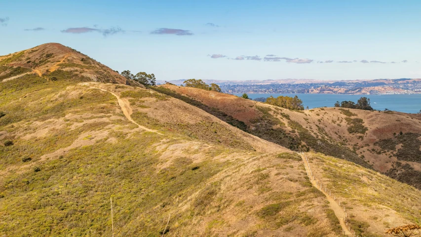 an overview from above a grassy hill towards water and mountains