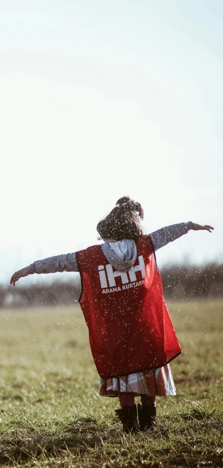 a woman wearing a red vest in a field holding an arm