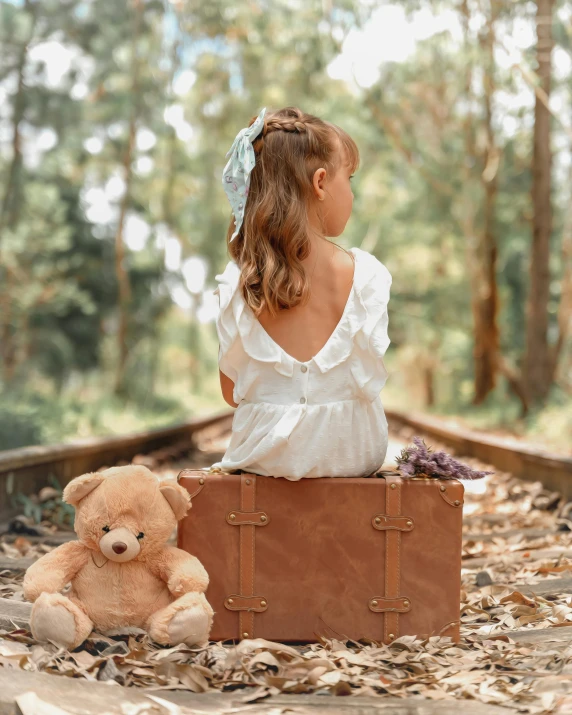 a little girl sits on top of a suitcase