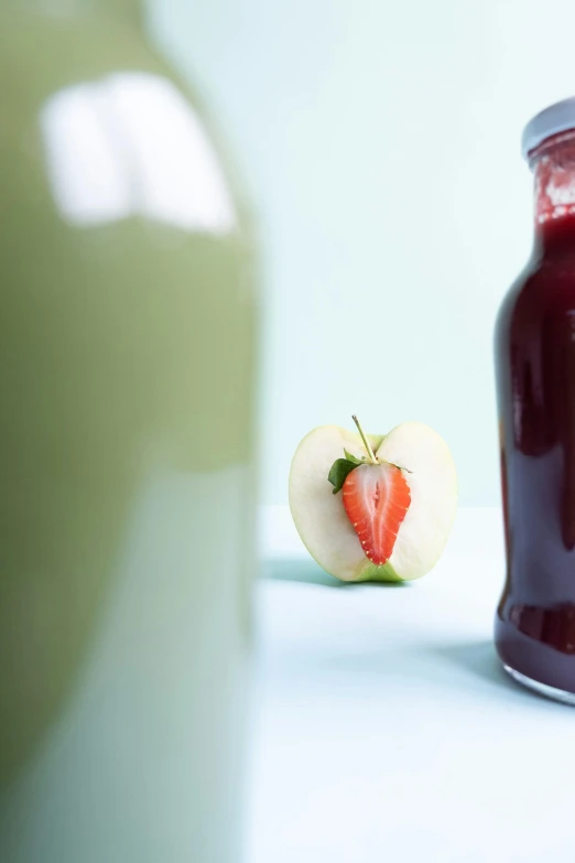 the apple is next to the jar of fruit juice