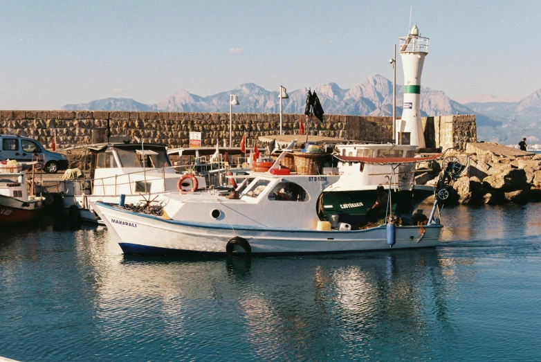 a fishing boat in the port with some ships docked