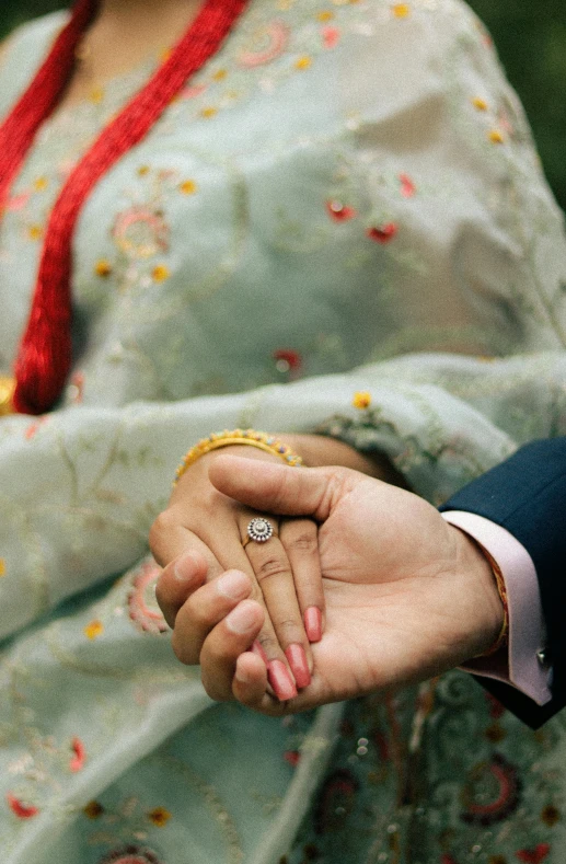 woman holding up a yellow wedding ring with one hand