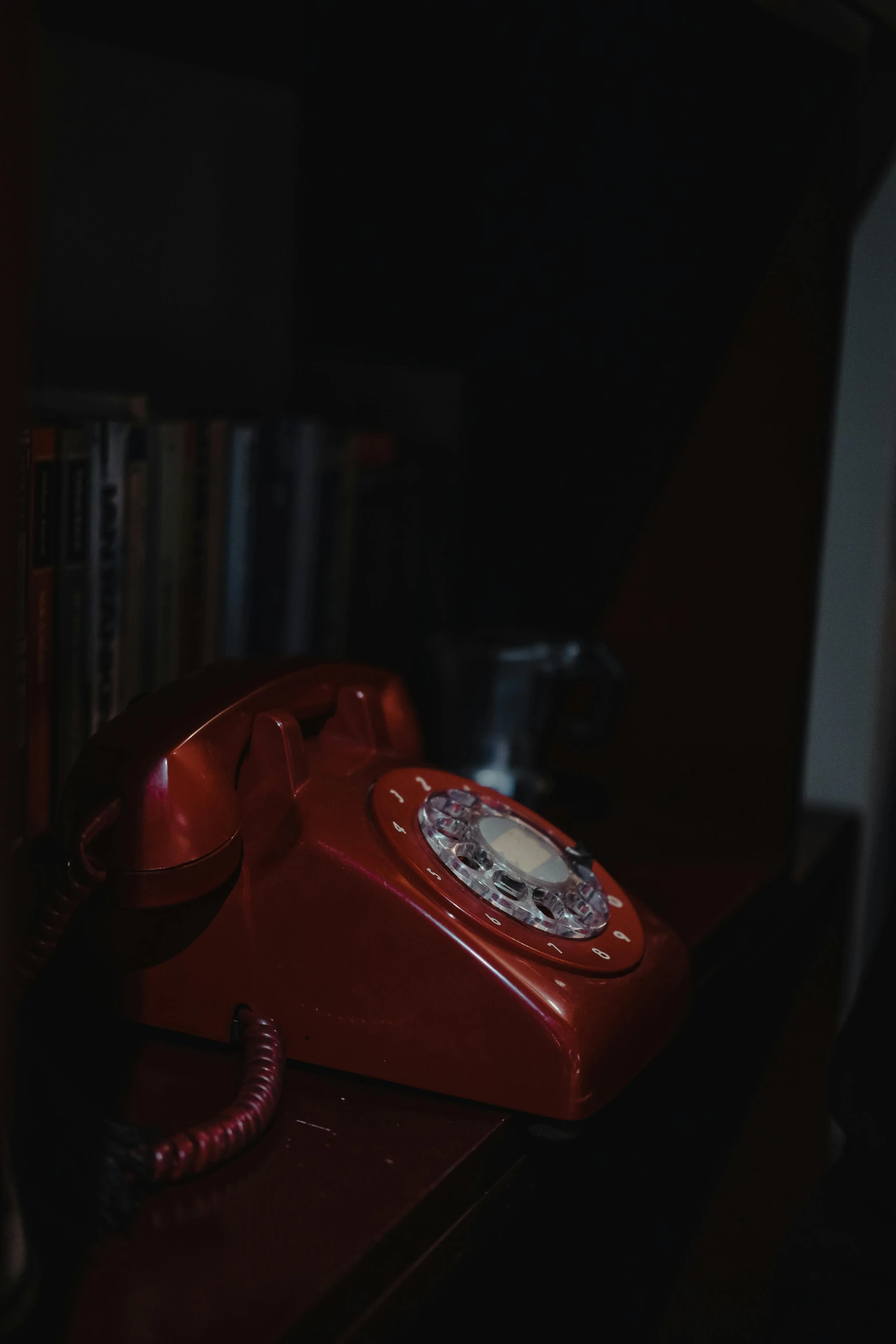 a red telephone is on top of a book shelf