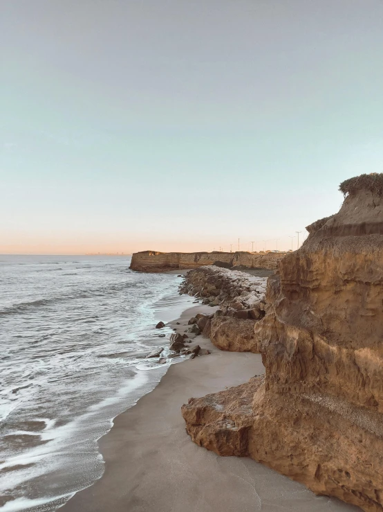 beach and rocky cliff at sunset near ocean