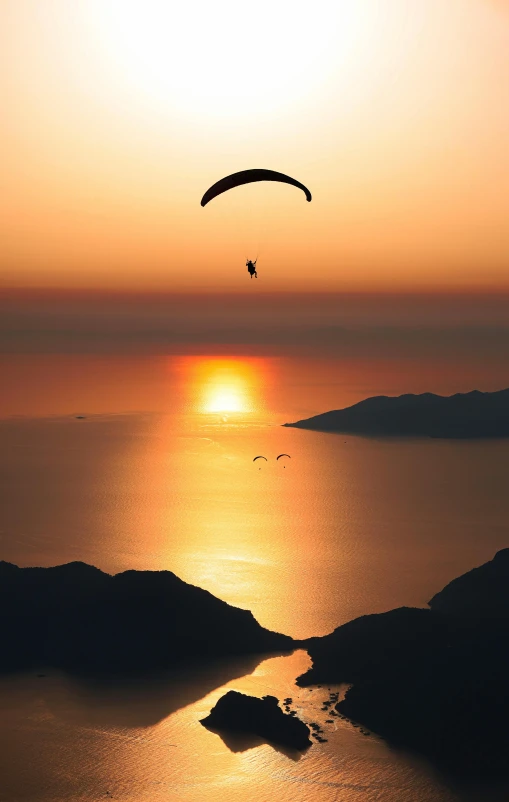 a person is paragliding over water at sunset