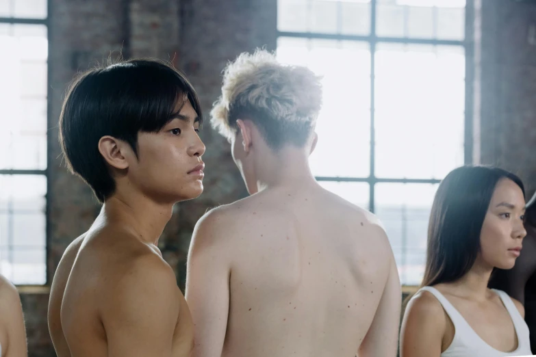 two guys standing side by side with their bare backs turned