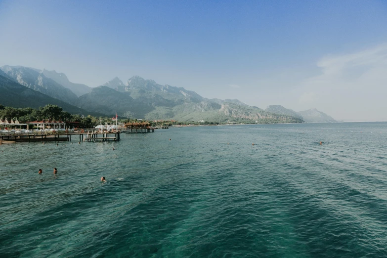 many people are swimming in the water near a shore line