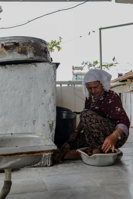 a woman in a white turban kneeling down to cook some food