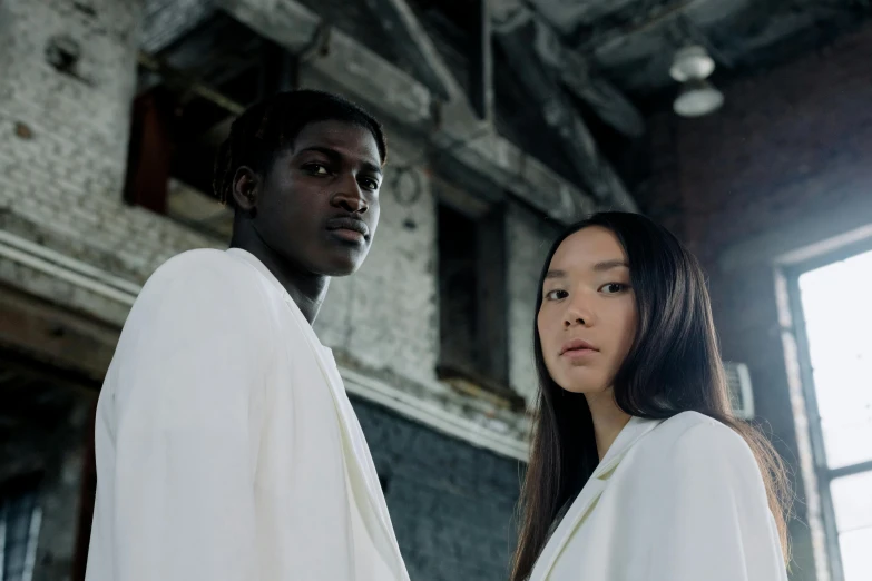 a man and a woman wearing white are standing together in an old industrial building