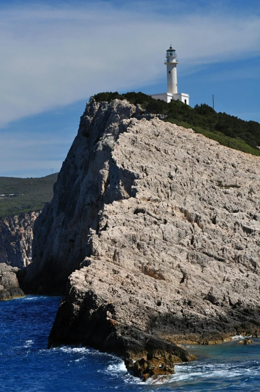 a lighthouse near the ocean surrounded by mountains