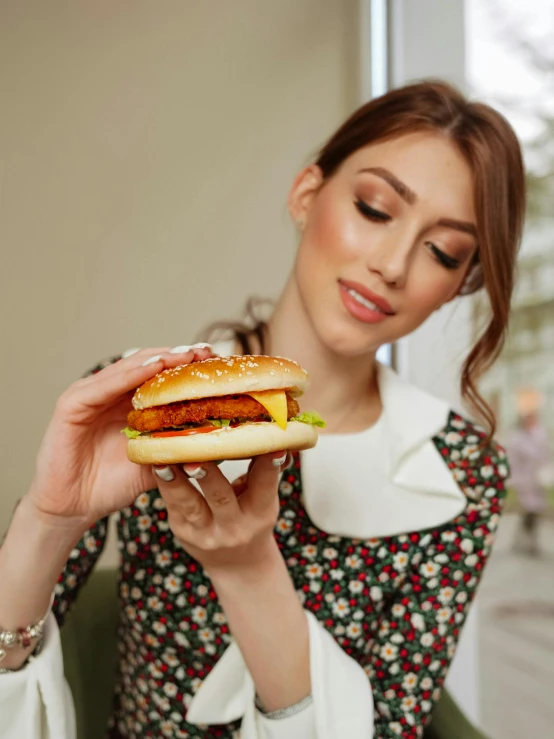 a woman wearing a floral dress is eating a sandwich