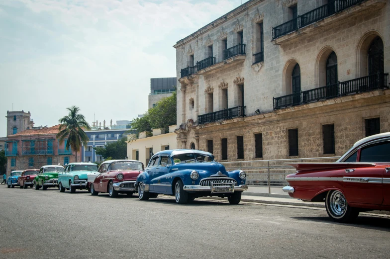 several classic cars are parked along a city street