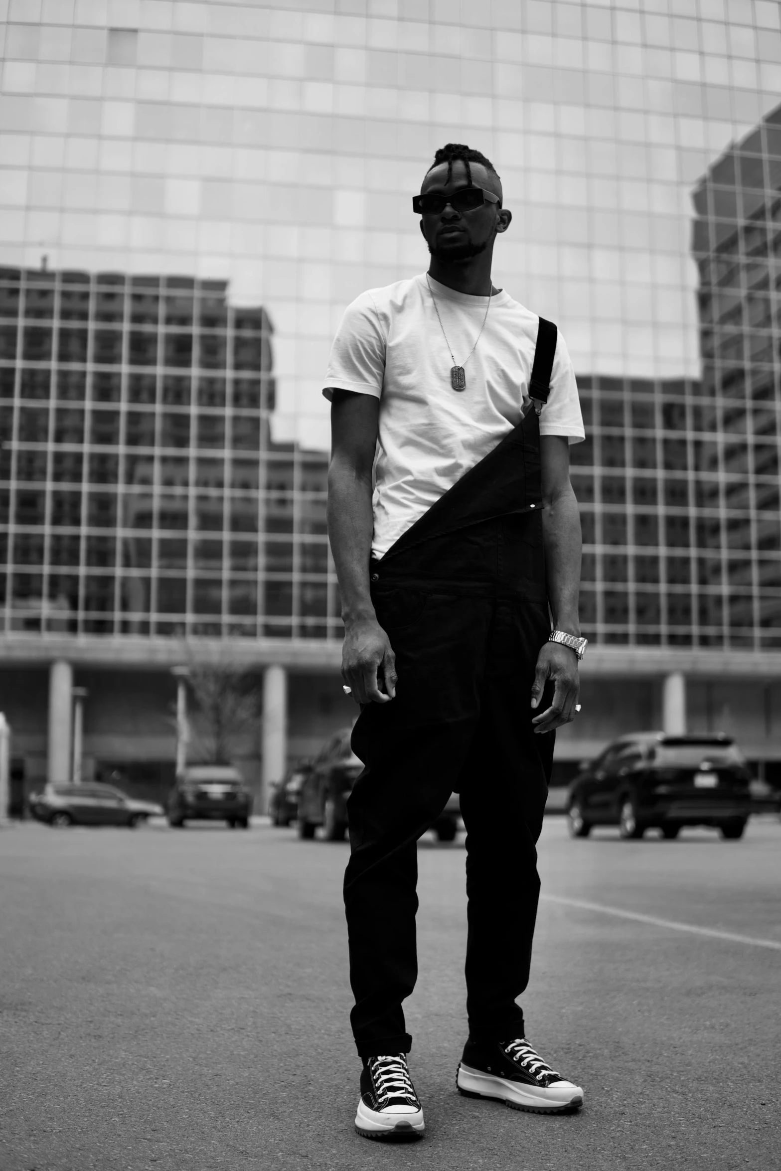 a man in overalls stands in front of a large building