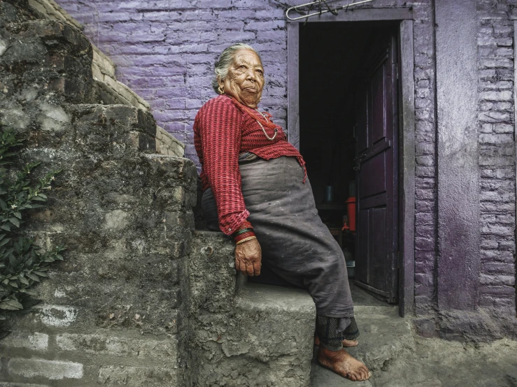 the elderly woman is posing on the rock outside