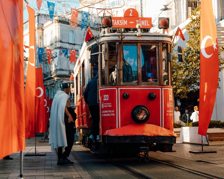 a vintage trolley car on tracks surrounded by flags