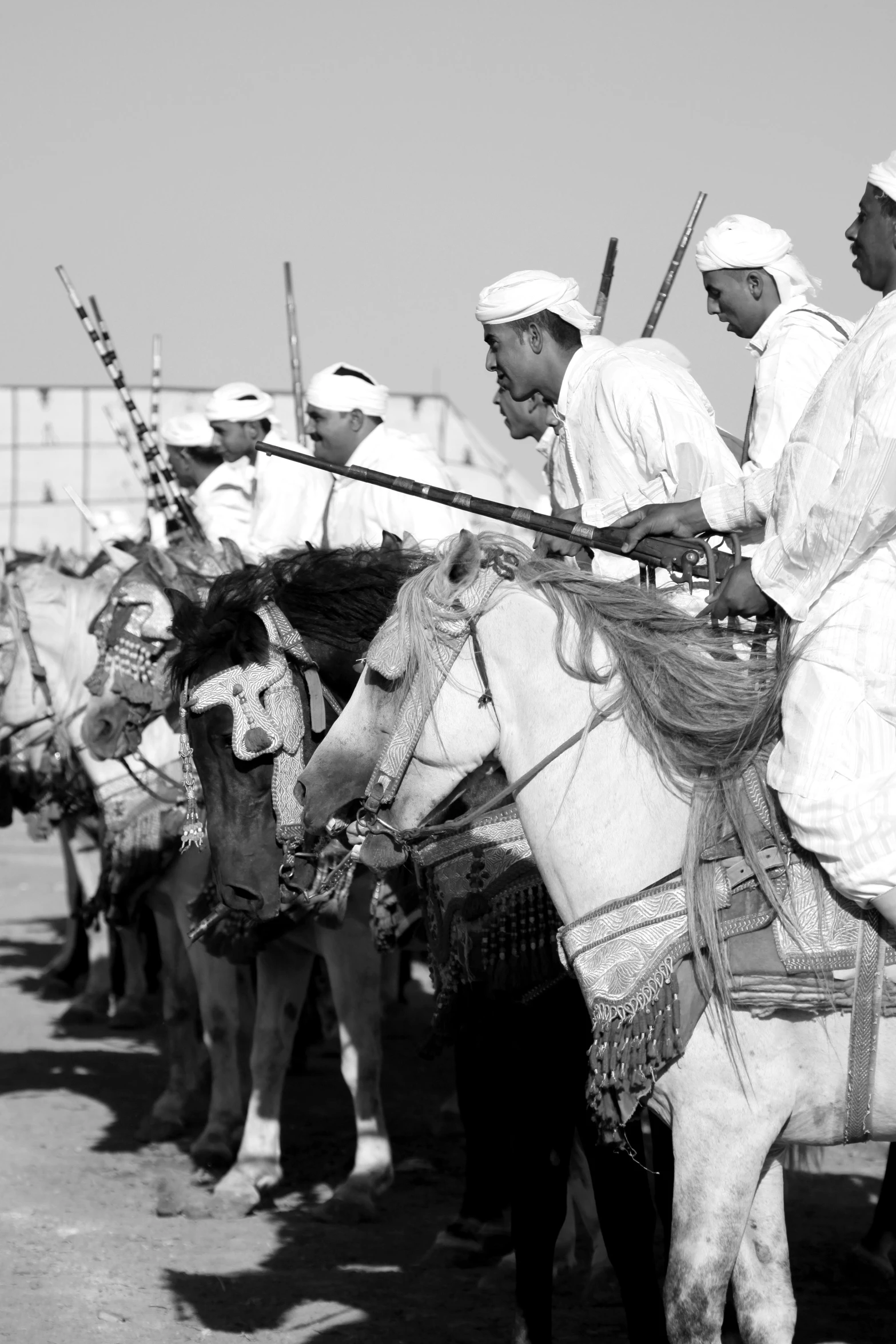 men are dressed in white on horseback in the desert