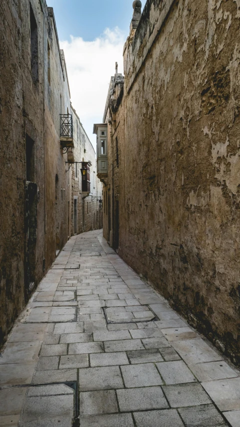 a narrow stone street with cobblestone and old buildings