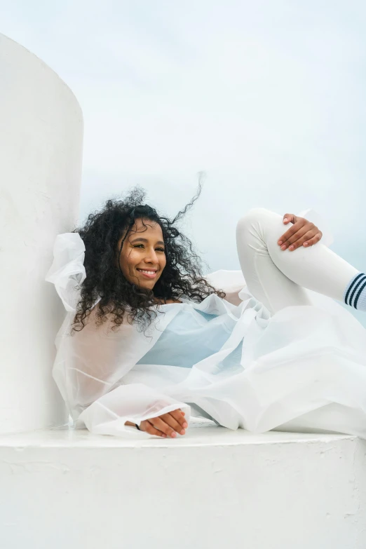 a woman in white clothing sitting on a white column