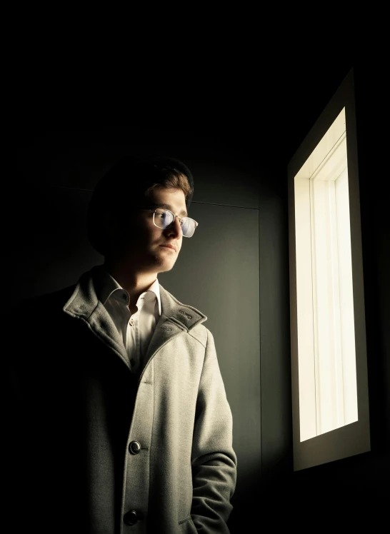 a man in a coat looking out of a window