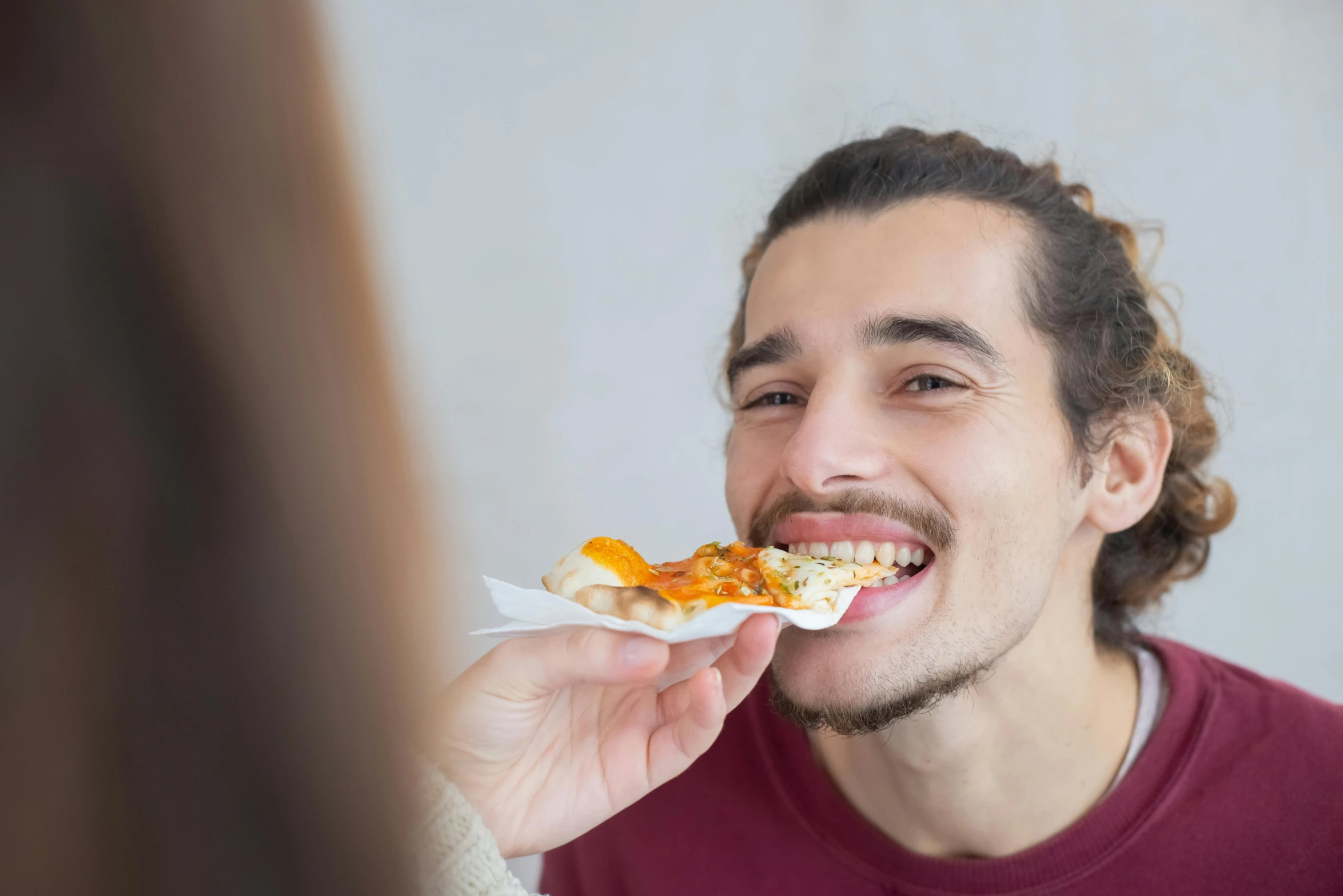 a man in red shirt eating food with a smile