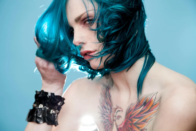 woman with turquoise hair is holding her face to her right