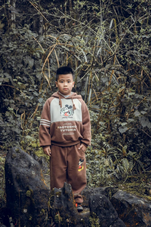 a boy standing in a clearing surrounded by some rocks and trees