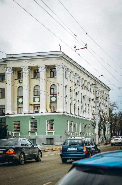 cars driving down the street in front of a white building