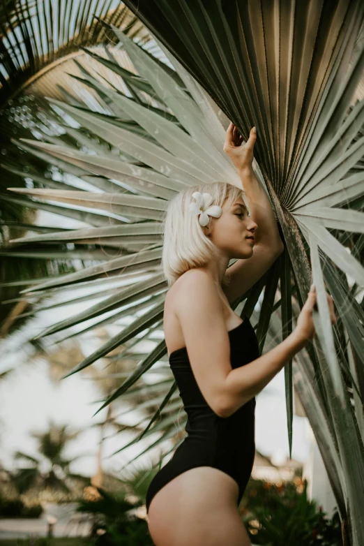 a woman in a bathing suit standing next to a palm tree