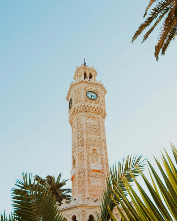 a large tall clock tower sitting behind green trees