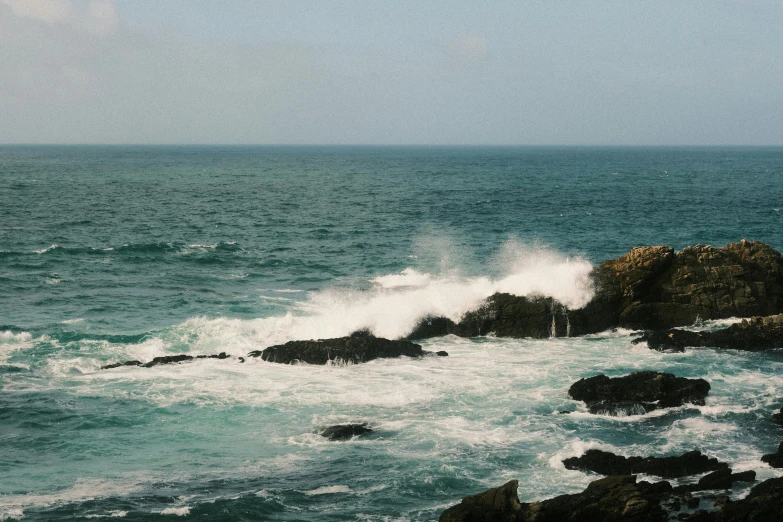 a wave crashing onto rocks in the ocean