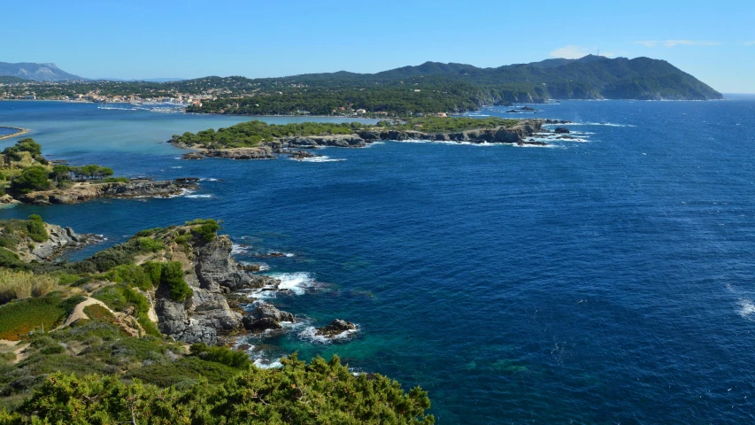 a view from the top of a hill in a wooded area near the ocean and with water