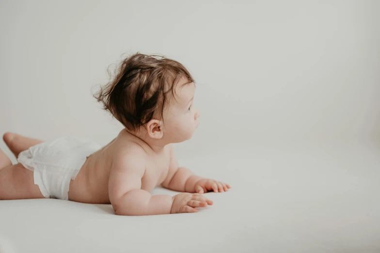 an infant lays on it's back against a white backdrop