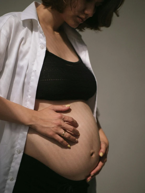 a pregnant woman holding her belly in the dark