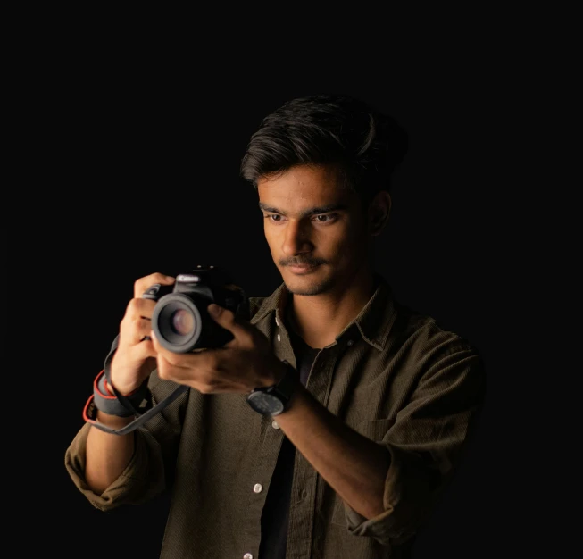 a man holding up his camera in front of a dark background