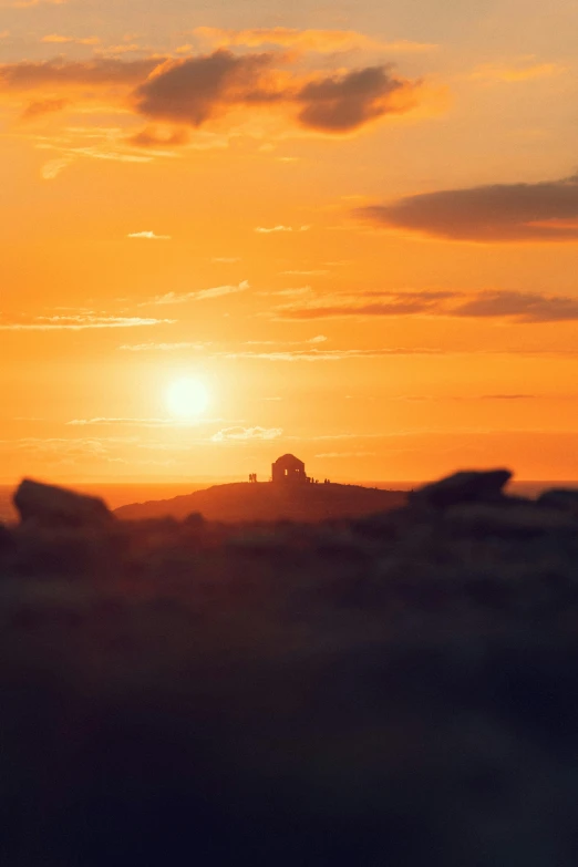 sunset in the background with large rocks and grass