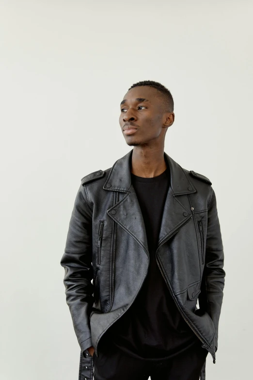 a man standing in black pants and a leather jacket