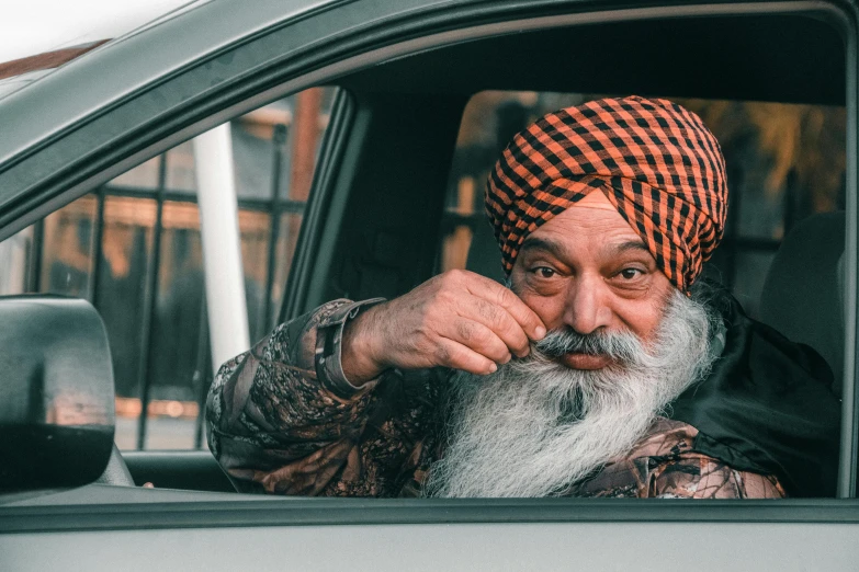 an old man with a large beard sitting in a car